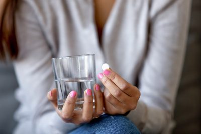 Woman with water and medication Getty Images 1157025908